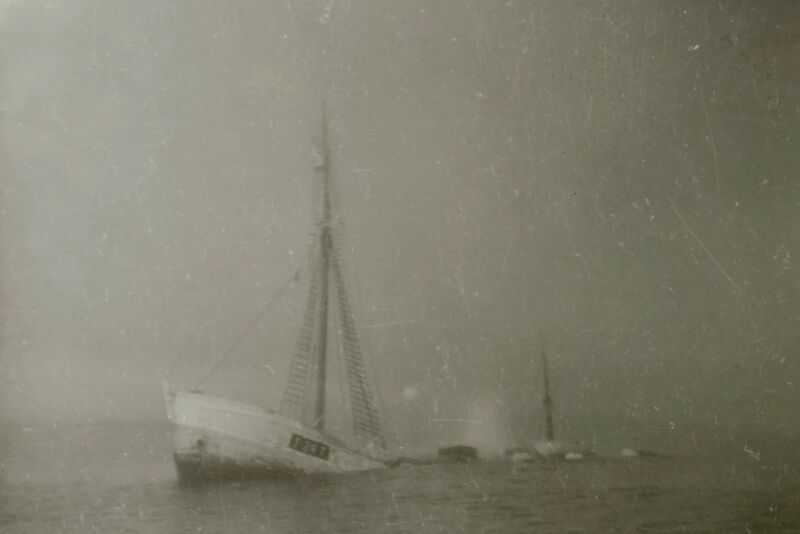 Ghostly historical black and white photo of a ship breaking in two in the process of sinking