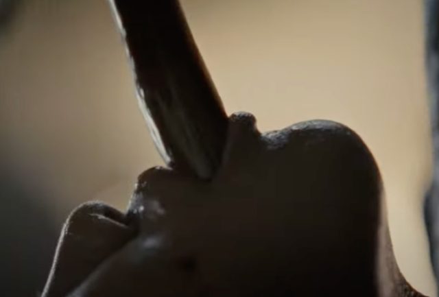close of person's head with long tentacle coming out of their mouth