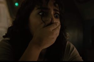 dark haired woman with hand over her mouth gasping in horror