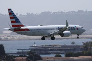 An American Airlines plane just before making a landing with a body of water in the background