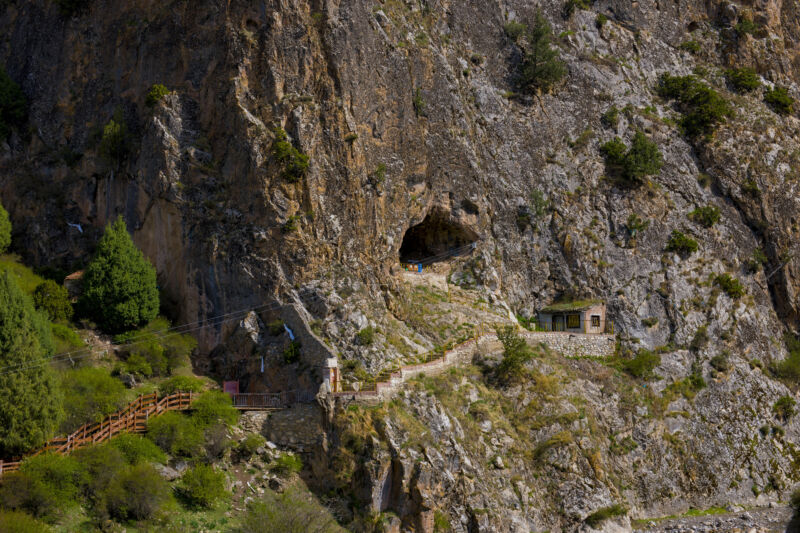 Image of a steep cliff with a narrow path leading to a cave entrance.