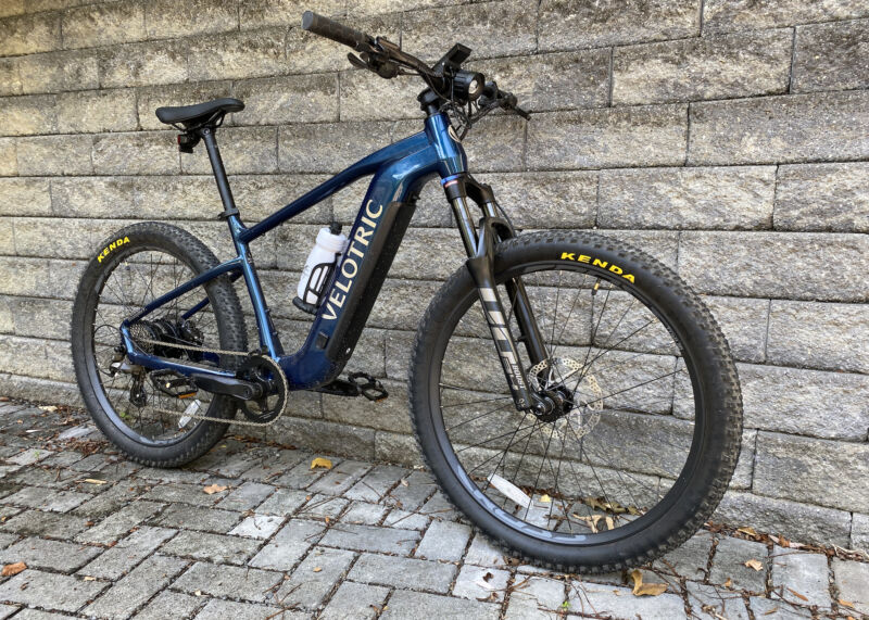 Image of a blue hard tail mountain bike leaning against a grey stone wall.