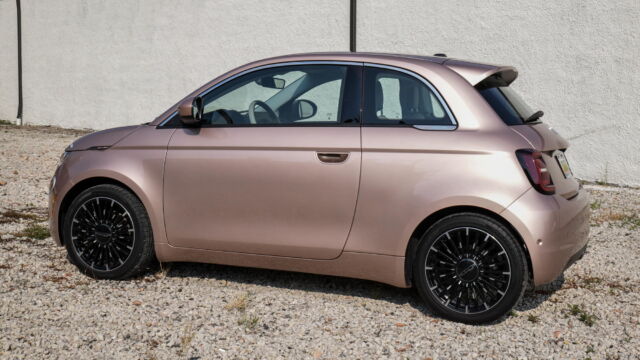 A rose gold car stands out in a sea of monochrome SUVs.