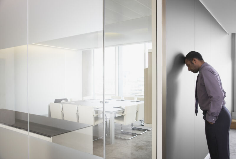 Businessman leaning on corridor wall