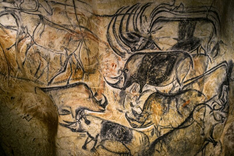 Image of a tan rock surface with black and brown depictions of animals on it.