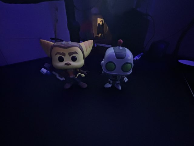 Collectible figurines in dark blue light; the image is grainy and missing detail