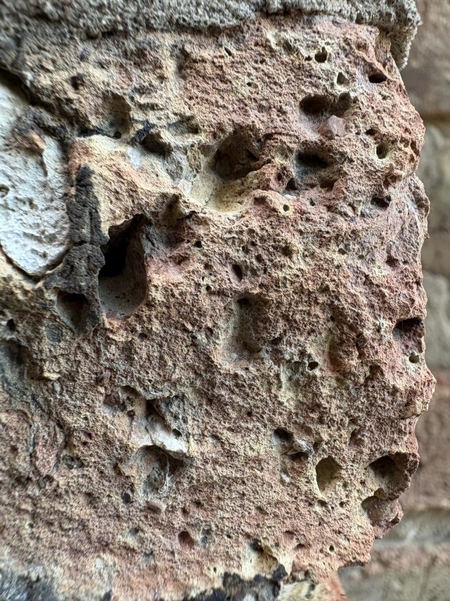 A detailed close-up of a brick, with holes and damage visible