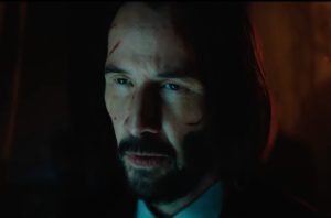 closeup of Keanu Reeves as John Wick with mustache and goatee and several cuts on his face