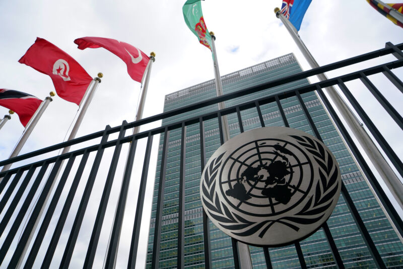 Emblem of United Nations with UN member country flags and Secretariat Building in the background