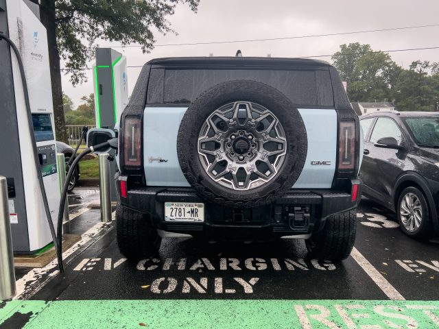 A Hummer EV SUV seen from the rear, at a charging location