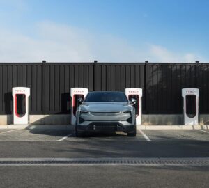 A Polestar 2 EV parked in front of a bank of Tesla Superchargers