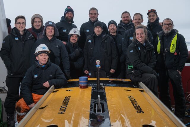 Endurance22 Expedition crew members stand proudly with the AUV they used to find the Endurance