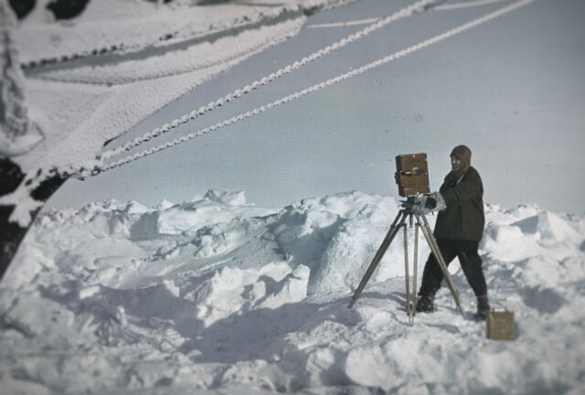 Frank Hurley with a camera under the bow of the Endurance.