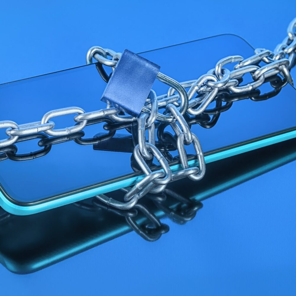 A smartphone wrapped in a metal chain and padlock