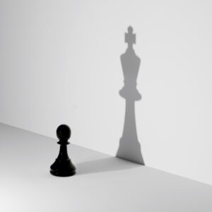 A pawn chess piece sees its shadow in the form of a king.