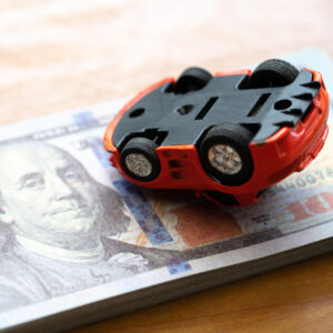 An upside-down toy car on a stack of $20 bills