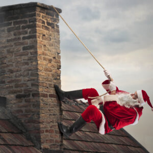 A photograph of an old man dressed as santa claus climbing on the side of a chimney with the help of a rope