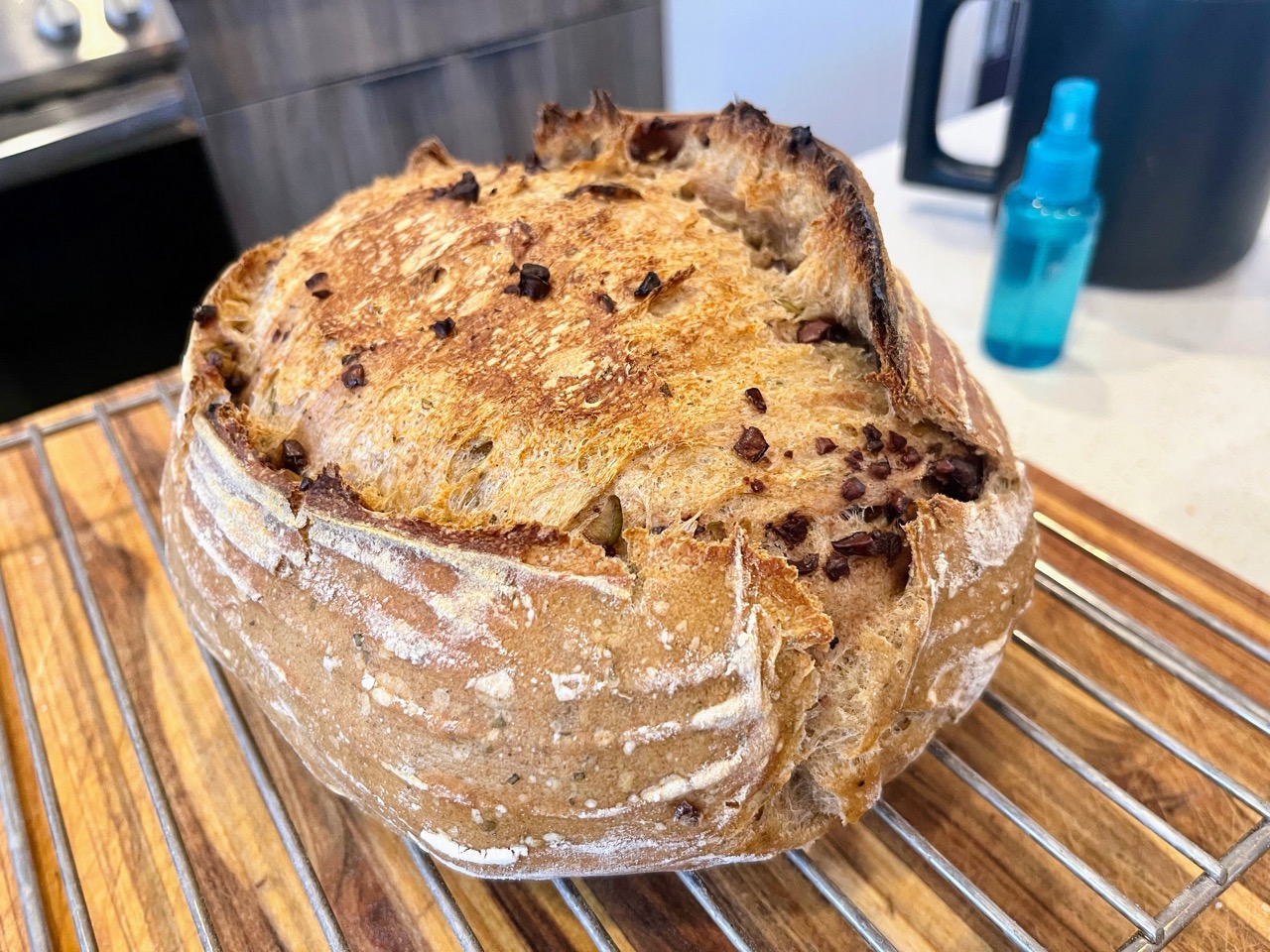 Loaf that is split across the middle-top, with flecks of olives showing.