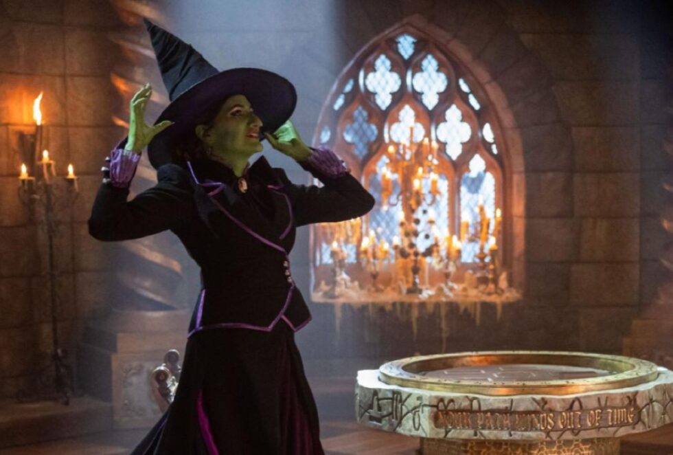 Woman dressed as the green-skinned Wicked Witch of the West, all in black with a pointy hat