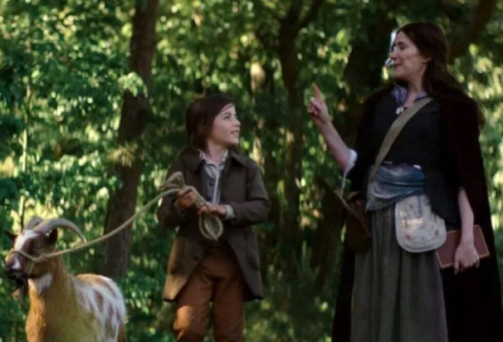 Little boy and his mother in 18th century garb walking along a path in the woods