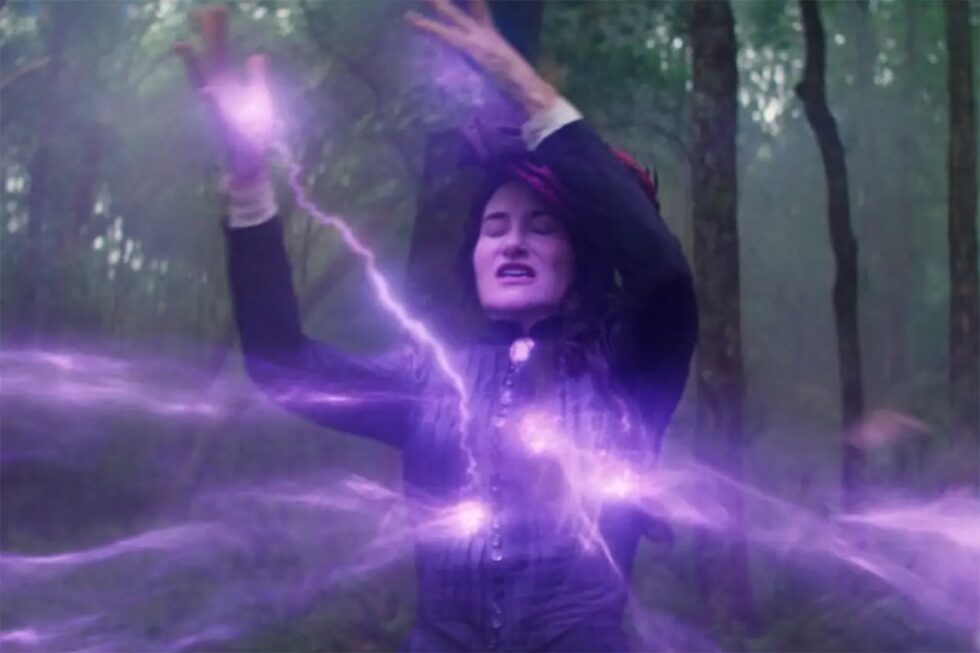 Dark haired woman with hands outstretched absorbing power represented by lightning bolds of purple light.