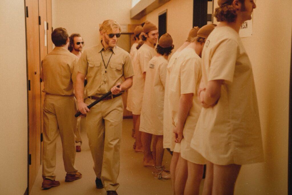 guards dominate prisoners lined up along the wall.