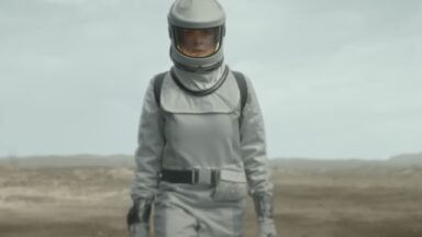 woman in white space suit walking across a desolate plain