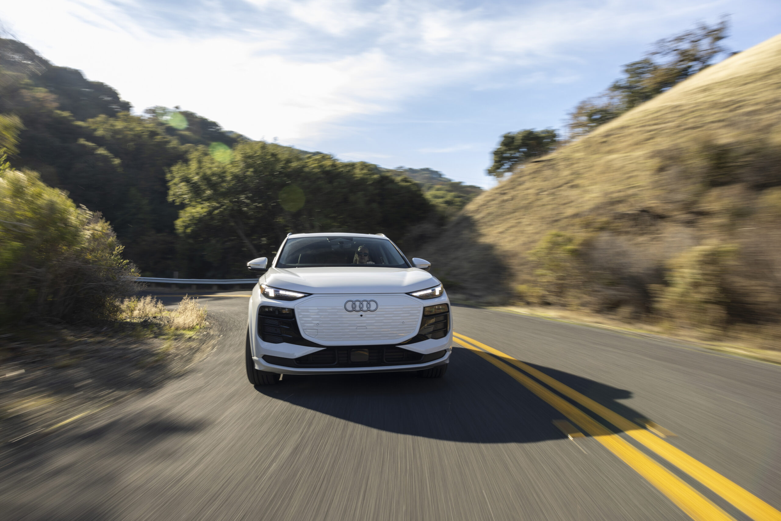 A white Audi Q6 drives towards the camera