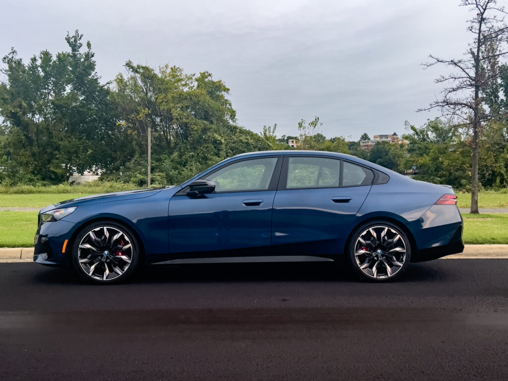 A blue BMW i5 in profile