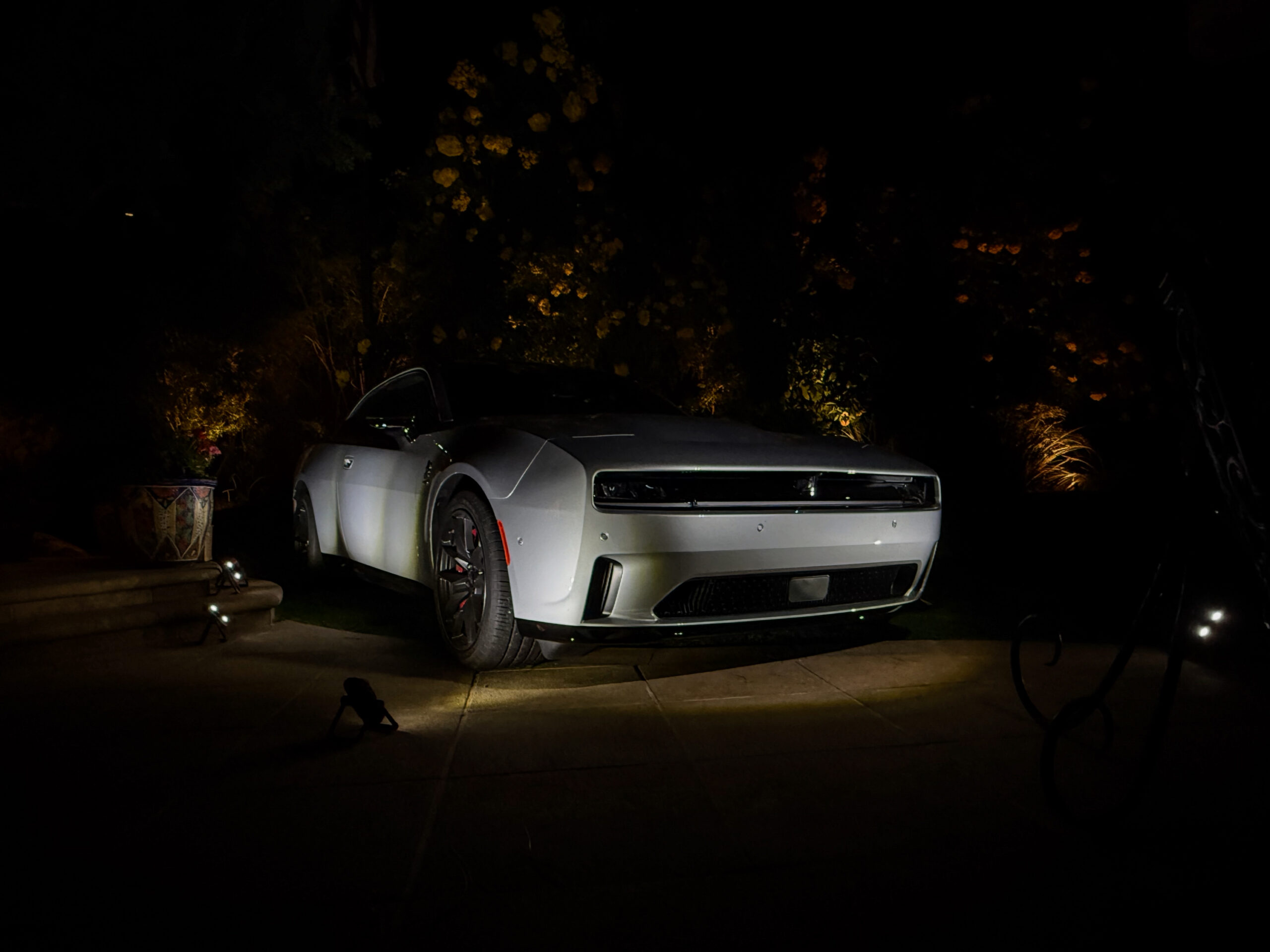 A silver Dodge Charger Daytona is partially illuminated at night