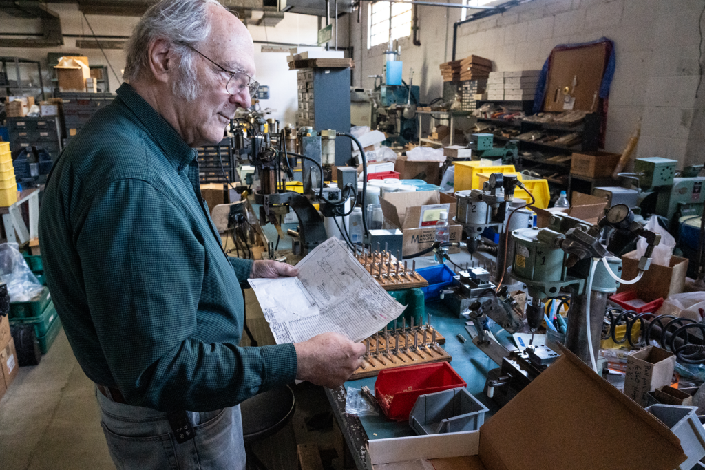 A man reads a schematic at a work desk