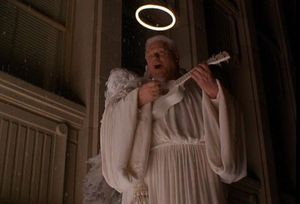 older man in angel garb, wings, and a halo playing a white ukelele