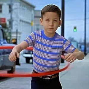 little boy in striped shirt and jeans playing with a hula-hoop