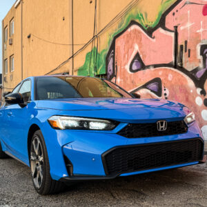 A blue Honda Civic parked next to some graffiti.