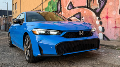 A blue Honda Civic parked next to some graffiti.