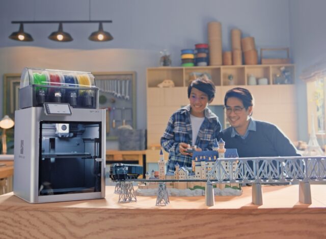 Father and son smiling while looking at something akin to a train bridge, with a photoshopped Bambu Labs X1 inserted nearby.