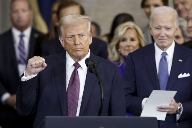 US President Donald Trump holds up his right hand in a fist after being sworn in at his inauguration on January 20, 2025 in Washington, DC. Former President Joe Biden stands behind Trump.