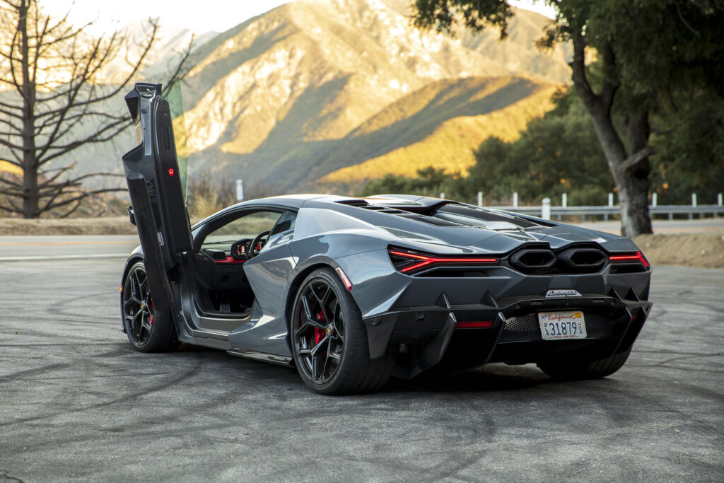 Lamborghini Revuelto seen from behind with the door open, there are mountains in the distance.