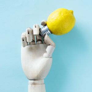 A robot hand holding a lemon-shaped light bulb.