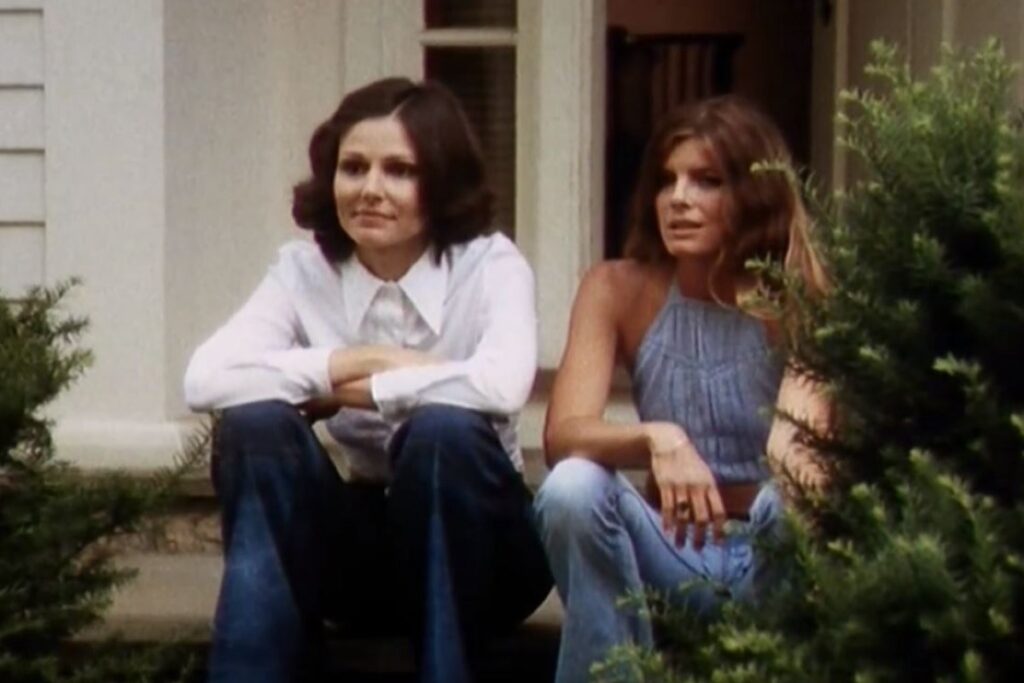 two woman sitting on a stoop and chatting.