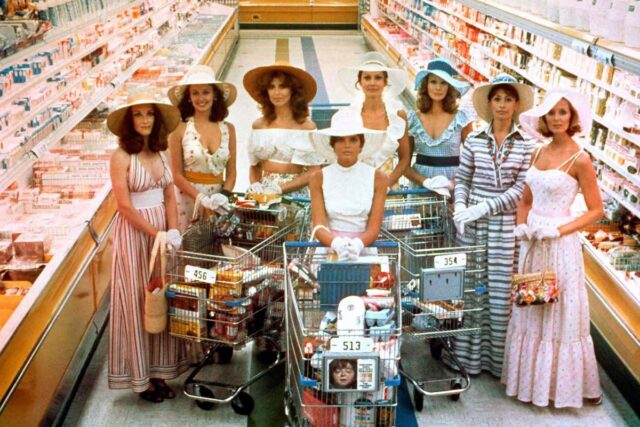 group of traditionally dressed women in grocery store with carts, looking at camera.