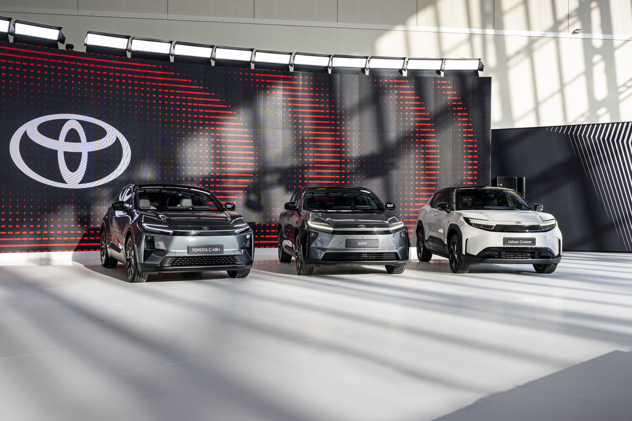 Three electric Toyotas on display in front of a Toyota banner