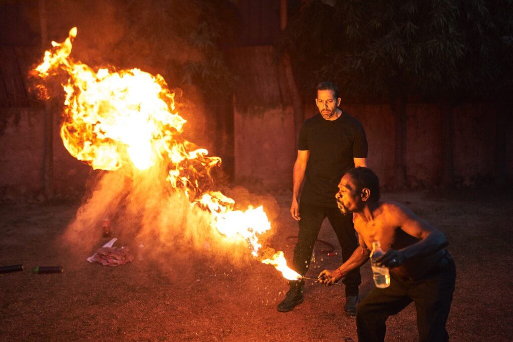 Fire Ramesh demonstrates spitting a fireball for Blaine.