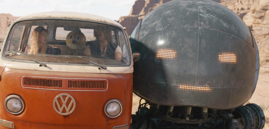 orange and white van being flanked by a large gray robot head.