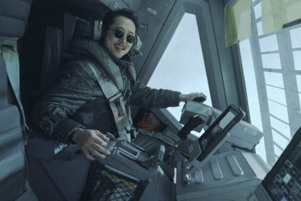 Asian guy in uniform and sunglasses sitting in the cockpit of a spacecraft