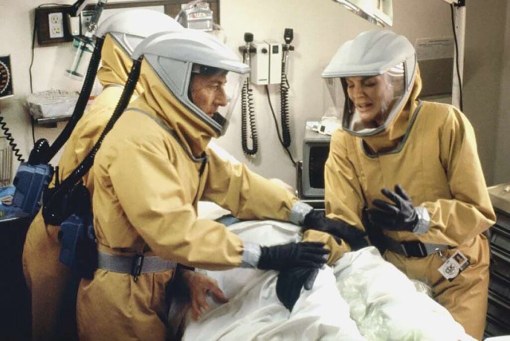 man and woman in full lab hazmat gear examining a body