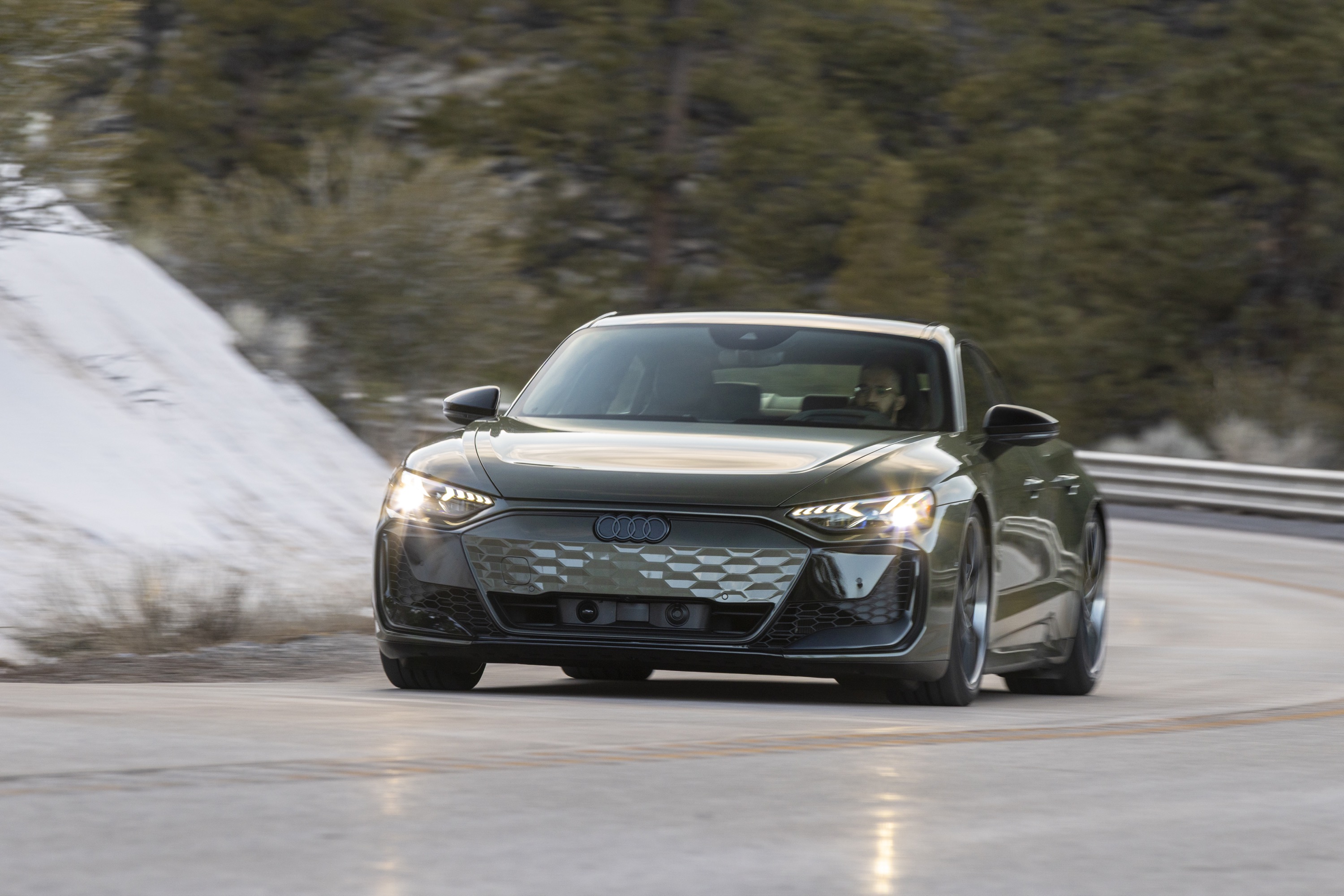 A green Audi RS e-tron GT drives on the road