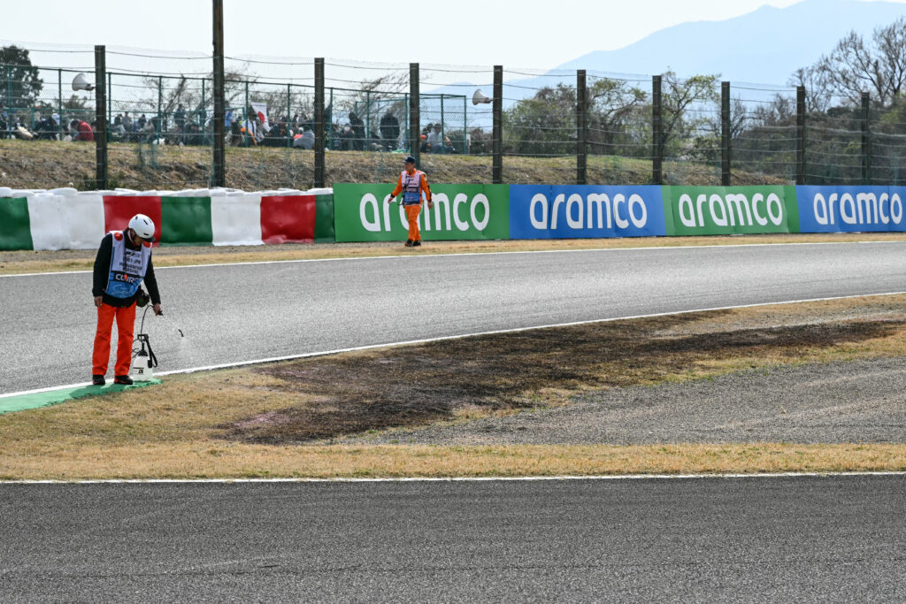A track marshal (L) waters down the dried out grass next to a burnt patch (C), along the side of the track ahead of the qualifying session of the Formula One Japanese Grand Prix at the Suzuka circuit in Suzuka, Mie prefecture on April 5, 2025. The third practice session early was again interrupted by trackside fires as sparks from the cars ignited the grass in the dry conditions. A small fire broke out about 10 minutes into the session and another brought out the red flags for a second time in the closing minutes.