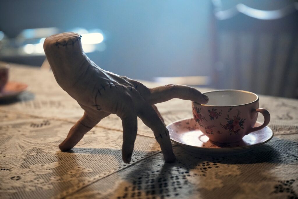 detached hand with forefinger touching a teacup