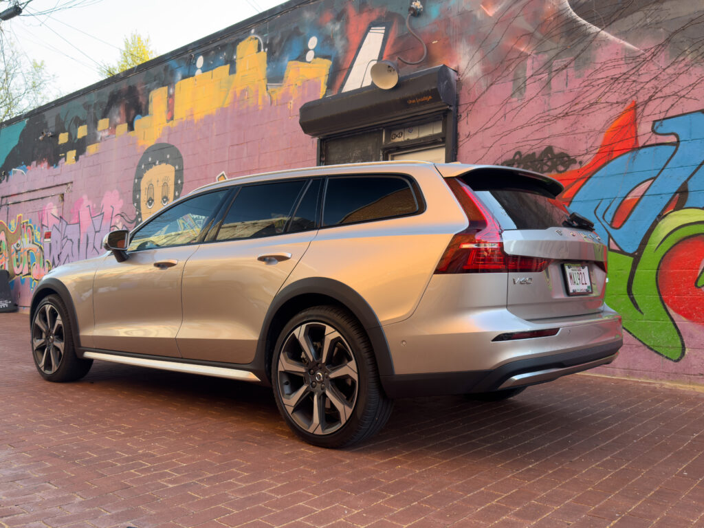 A Volvo V60 Cross Country parked in front of a mural, seen from the rear 3/4s